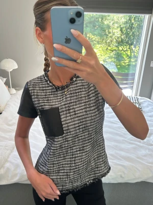 Svartvit topp med skinnärm  - Säljer en svartvit topp med korta ärmar i skinnimitation och en matchande bröstficka. Från ett New York baserad märke, Rebecca taylor! Köpt där så unik då inte många har denna toppen här hemma. Fint skick! Size 2, motsvarar en S.