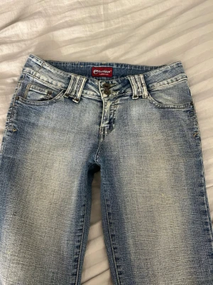 Bootcut vintage jeans  - Blåa bootcut vintage 2000s jeans med slitningar och klassisk femficksmodell. Jeansen har låg midja och utsvängda ben, perfekta för en snygg och trendig look. Dem har en snygg och archive vintage design som är svår att få tag i. Materialet är denim i bomull med en tvättad effekt. Jag säljer jeansen pga att de blev på snudd för korta för mig då jag är 165 cm lång. 
