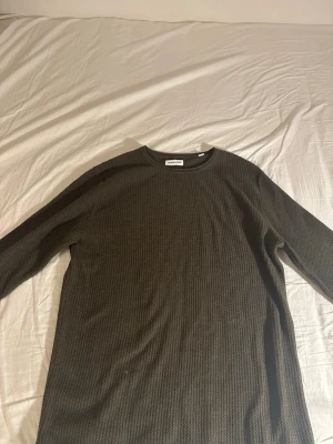 Mörkgrön stickad tröja Jack & Jones - Säljer en mörkgrön stickad tröja från Jack & Jones. Tröjan har rund halsringning och är ribbstickad med lång ärm. Perfekt för dig som gillar en enkel och stilren look med lite struktur i materialet.