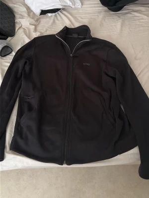 Svart ziptröja från BOSS - Snygg svart ziptröja från BOSS med diskret logga på bröstet. Tröjan har hel dragkedja, ståkrage och två sidofickor med dragkedja. Perfekt för en clean och stilren look. Materialet känns mjukt och bekvämt. Det är storlek M men passar S. Den är köpt för 1600kr 