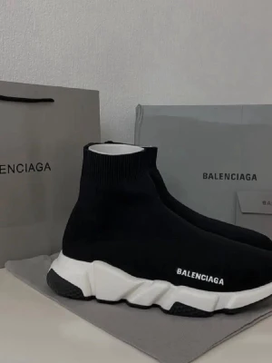 Speed Trainer svarta sneakers - Svarta Speed Trainer sneakers med vit chunky sula och stickad ovandel i stretchigt material. Modellen har en strumpliknande passform och är perfekta för dig som gillar en modern och sportig look.