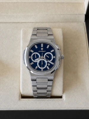 Stilren silverklocka med blå urtavla - Snygg klocka i rostfritt stål med länkarmband och blå urtavla. Klockan har tre subdials och markerade index, vilket ger en modern och sportig look. Perfekt accessoar för dig som gillar stilrena detaljer och metalliska toner.