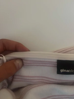 Randig tubtopp från Gina Tricot - Säljer en söt tubtopp i vit med ljusrosa ränder. Använd max tre gånger och har välbehållits bra! Kan även användas som kjol!❤️ kom gärna med prisförslag!