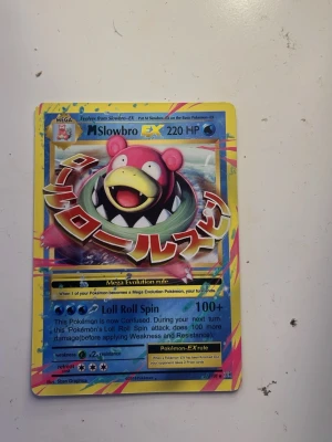 Pokémonkort Mega Slowbro EX - Säljer ett färgglatt Pokémonkort av typen Mega Slowbro EX med 220 HP. Kortet har en cool design med japansk text och blå, rosa och gula detaljer. Perfekt för samlare eller Pokémonfans som vill utöka sin kortlek.