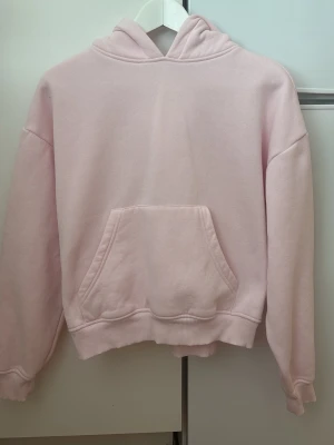 Ljusrosa hoodie med magficka - Säljer en ljusrosa hoodie med huva. Hoodien har ribbade muddar vid ärmslut och nederkant, samt en avslappnad passform. Perfekt för dig som gillar en enkel och stilren look. Materialet känns mjukt och skönt mot huden.