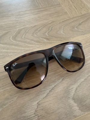 Ray-Ban Boyfriend 4147 - Säljer ett par snygga solglasögon från Ray-Ban med klassisk wayfarer-form. Bågarna är brunmelerade och glasen är tonade i brunt. Perfekta för soliga dagar och ger en cool vibe till din outfit.