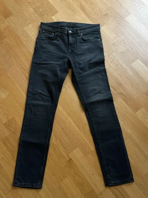 Svarta nudie jeans Lean Dean - Snygga svarta Nudie Jeans i modellen lean dean. Ett par slim fit jeans med klassisk femficksdesign. Jeansen har raka ben och normal midja. Använda en gång pga för stor storlek.