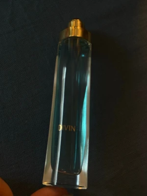 Oriflame Divine parfym blå glasflaska - Snygg parfym från Oriflame i modellen Divine. Flaskan är smal och elegant i blått glas med guldfärgat lock. Doften är blommig med inslag av hyacint, viol, bambu, ros, lilja, jasmin, fresia, plommon, sandelträ och mysk. Eau de parfum.