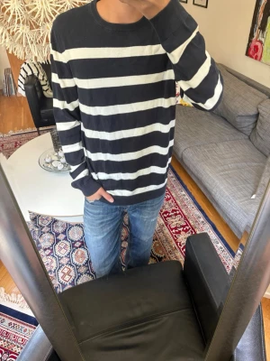 Randig marinblå och vit tröja - Snygg långärmad tröja med breda marinblå och vita horisontella ränder. Tröjan har rund halsringning och ribbade muddar vid ärmslut och nederkant. 