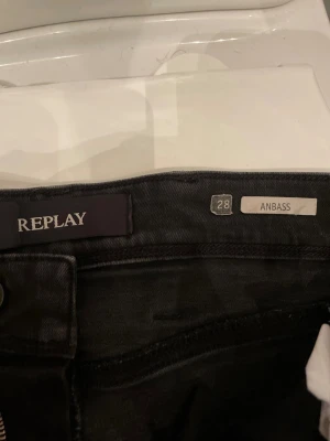 Säljer mina svarta AMBASS Reaplay jeans nu för 349kr - Svarta Replay Anbass jeans i klassisk femficksmodell med snygga detaljer och diskret logga på fickan. Jeansen har en smal passform och är tillverkade i stretchig denim för extra komfort. Perfekta för dig som gillar stilrena och moderna jeans. I storlek w28 L32