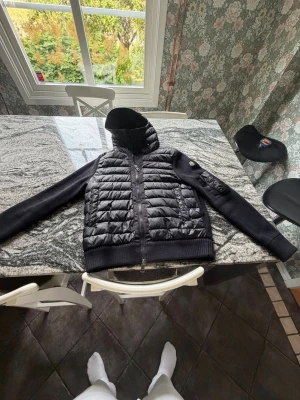 Svart dunjacka från Moncler - Snygg svart moncler cardigan i bra skick det ända är ett litet hål på vänster bröst men inget man lägger märke till eller tänker på.