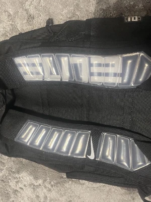 Svart Nike Elite ryggsäck - Säljer en svart Nike Elite ryggsäck med vita detaljer och logga. Ryggsäcken har vadderade axelband med texten 'ELITE' och smarta fack för förvaring. Materialet är slitstarkt tyg och botten är förstärkt för extra hållbarhet. Perfekt för träning eller skola.