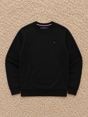 Svart sweatshirt från Tommy Hilfiger - Klassisk svart sweatshirt från Tommy Hilfiger med rund halsringning och diskret logga på bröstet. Tröjan har ribbade muddar vid ärmslut och nederkant. Perfekt basplagg för en clean och stilren look.