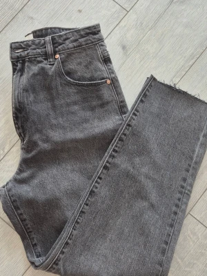 Grå mom jeans - Ny oanvänd grå mom jeans med hög midja och raka ben. Jeansen har fem fickor, knappgylf och rå, avklippt kant vid bensluten. Storlek kolla bild 5
