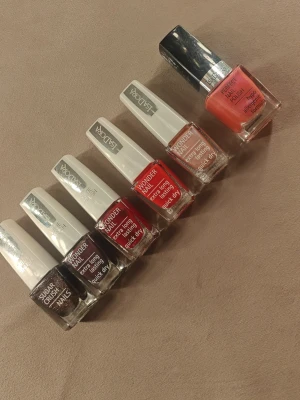 Isadora nagellack i 6 olika färger - Säljer ett set med sex nagellack från Isadora. Färgerna inkluderar svartglittrigt (Sugar Crush), mörklila, vinröd, röd, shimmer rosa och en korallrosa nyans. Flaskorna har bred pensel för enkel applicering och ger extra lång hållbarhet. Perfekt för dig som vill variera din nagellook.