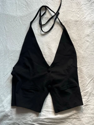 Kostym festtopp - Snygg festtopp i kostymmaterial och utseende. Man knyter den i nacken och i ryggen passar perfekt med kostymbyxor men även jeans. Från gina tricot andvänd 1 gång