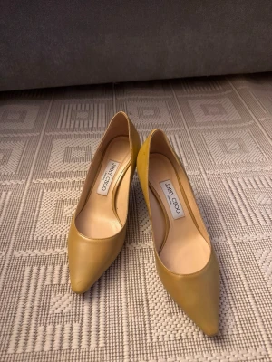 Gula pumps från Jimmy Choo - Snygga gula pumps från Jimmy Choo i slätt läder. Skorna har spetsig tå och klassisk siluett som ger en elegant look. Perfekta för dig som vill sticka ut med färg och stil.