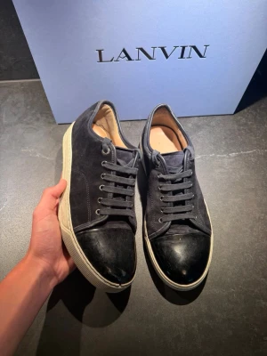 Svarta Lanvin sneakers i mocka och läder - Hejsan! Säljer nu dessa riktigt feta skor i från lanvin! Dem är i storlek 42 men passar 43! Bra skick kvitto och box hänger med vid köp! Hör av er vid frågor!