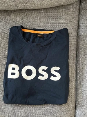 Mörkblå BOSS t-shirt med stor logga - Snygg svart t-shirt från BOSS med stor vit logga över bröstet. Klassisk rund halsringning och korta ärmar. Storlek L