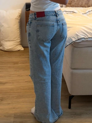 Ljusblå baggy jeans med slitning - Säljer ett par ljusblå baggy jeans med hög midja och raka ben. Jeansen har slits på insidan och ett hål på ena knät!