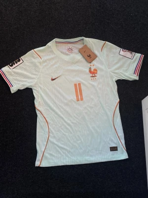 Frankrike Bortaställ 2026 (Olise) - Säljer Frankrikes nya bortaställ (Player Version) för VM 2026 med Olise på baksidan. Den är helt ny, ingen användning och kommer med tags. Perfekt för fotbollsträning eller match.   