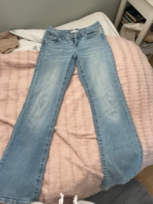 Ljusblå bootcut jeans - Säljer ett par ljusblå bootcut jeans med klassisk femficksdesign och låg midja. Jeansen är från Gina och är knappt använda och är i bra skick, sitter lite stort i låren och är lite stora i storleken.