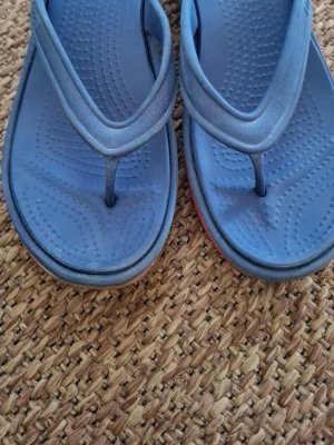 Blå flip-flop sandaler - Snygga blå flip-flop sandaler i syntetmaterial med bekväm fotbädd och klassisk tårem. Perfekta för sommardagar och strandhäng. Sula med lätt struktur för extra grepp.