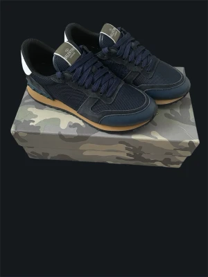 Valentino Garavani Sneakers Strl 41, Nyskick, Komplett - Säljer ett par exklusiva Valentino Garavani sneakers i storlek 41.  Skorna är använda sparsamt under cirka två månader och är i mycket fint skick. De är väl omhändertagna och ser nästan ut som nya.  Originalkartong samt samtliga tillbehör ingår: • Original dustbag • Extra originalsnören • Kort och etiketter • Originalkartong  En stilren och tidlös sneaker som passar både till vardag och mer uppklädda tillfällen.  Storlek: 41  Skick: Mycket fint skick  Pris kan diskuteras vid smidig affär