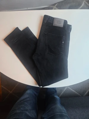 Svarta jeans från Replay - Snygga svarta jeans från Replay med klassisk femficksmodell och diskret logga på fickan. Jeansen har en rak passform och är tillverkade i ett mjukt denimtyg som ger en skön känsla. Perfekta för dig som gillar stilrena och tidlösa plagg.