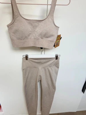 Beige träningsset Aimn - Beige träningsset från Aimn med topp och tights. Toppen är i storlek S med prislapp på och tightsen i M är använda en gång🤍