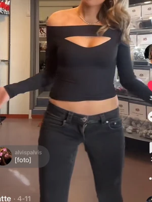 Svart offshoulder topp med cut out - Trendig svart offshoulder topp med lång ärm och snygg cut out-detalj vid bröstet. Toppen är croppad och har en tight passform som framhäver figuren. Perfekt för dig som vill ha en edgy och modern look.