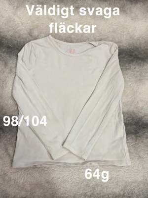 Vit långärmad topp från H&M - En enkel och stilren vit långärmad topp från H&M.   rund halsringning och normal passform. Perfekt basplagg till garderoben.🌸 Väldigt svaga fläckar. Storlek 98/104