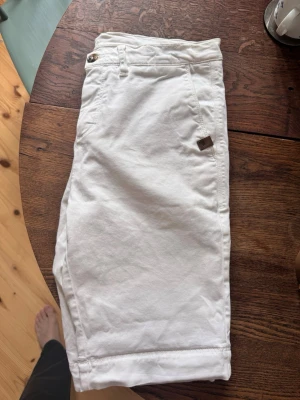 Sand copenhagen shorts - Snygga vita shorts i bomull med normal passform och midwaist. De har fickor fram och bak, bälteshällor och stängs med knapp och dragkedja. Perfekta för sommaren och enkla att matcha med olika stilar. Storlek 46