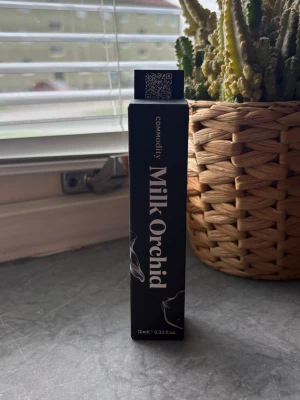 Commodity Milk Orchid parfym 10ml - Parfymen Commodity Milk Orchid kommer i en elegant svart rektangulär flaska med vit text och subtila rökdetaljer på förpackningen. Flaskan rymmer 10 ml och har en modern, minimalistisk design som känns lyxig och stilren. Ny 