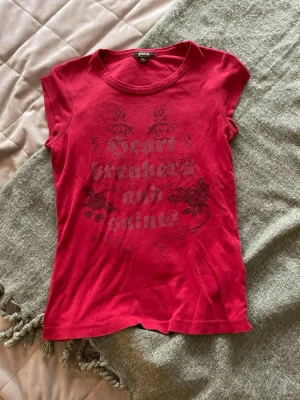 Röd topp med tryck från Peach - Fin röd t-shirt med tryck från Peach. Storlek 150. Det finns två små små hål vid märket, men man ser de inte.