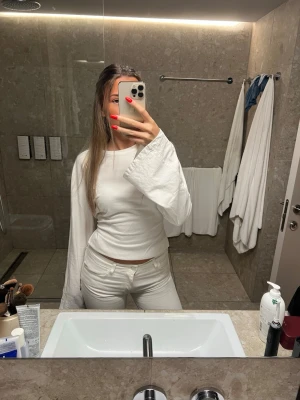Vit omlottopp med vida ärmar - Säljer en vit omlottopp med långa, vida ärmar och knyt i ryggen. Toppen är croppad och har en clean, minimalistisk look som passar perfekt till jeans eller kjol. Tillverkad i mjukt material som känns skönt mot huden.