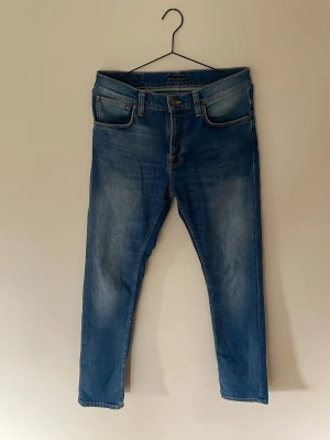 Blå jeans med smal passform - Säljer ett par klassiska blå jeans med smal passform och fem fickor. Jeansen har snygga slitningar framtill och bakfickor med dekorativ söm. Perfekta till en avslappnad stil och passar till det mesta i garderoben. Storlek W32 L32 se sista bild. Mycket bra skick! 