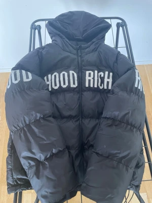 Svart pufferjacka med HOODRICH-tryck - Söker du en vinter jacka som är snygg och har reflexer som gör det omöjligt för bilarna att missa i mörkret ?  Nu har du chansen att köpa min hoodrich vinter jacka äkta från jd sports !   Den har växt ur mig och mina små syskon är för små för att ta över den annars hade ja själv velat ha den då den är så bra 😊 och varm   Tyvärr så är ena fickan på jackan sönder (högra fickan ) har du frågor eller funderingar hör av dig svarar så jag så fort som möjligt mvh daryan ❤️