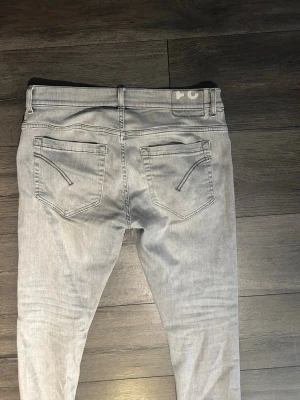 Gråa dondup george jeans  - Säljer ett par ljusgrå dondup George jeans. De är i bra skick förutom en liten defekt vid knäskålen (se sista bild) men det tänker man inte så mycket på vid användning. Vid frågor eller liknande är det bara att slänga iväg ett meddelande!