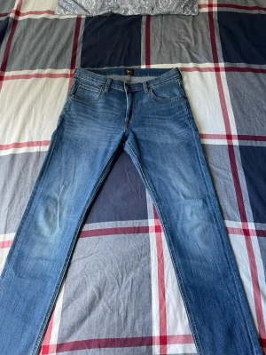 Blå jeans  - Säljer ett par klassiska blåa slimfit jeans från Lee i modellen Luke. Jeansen har en snygg tvätt och Lee-logga på bakfickan. Perfekta till vardags och lätt att matcha till olika outfits. Pris går att diskuteras vid snabb affär! Hör gärna av er om ni har några frågor eller funderingar! 