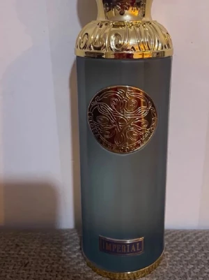 Gissah Imperial parfym 200ml - Lyxig parfymflaska från Gissah Signature Collection i metallicgrått med gulddetaljer och elegant mönster. Flaskan har en rundad form och dekorerad kork, och rymmer 200 ml doft. Märkt med 'Imperial' och tillverkad i Kuwait.