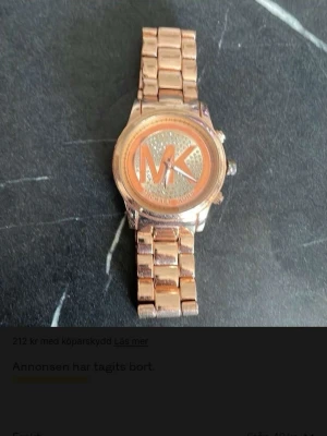 Roséguld klocka från Michael Kors - Snygg klocka i roséguld från Michael Kors med metallarmband och stor MK-logga på urtavlan. Urtavlan har glittriga detaljer och klockan har en klassisk länkdesign som ger en lyxig känsla.