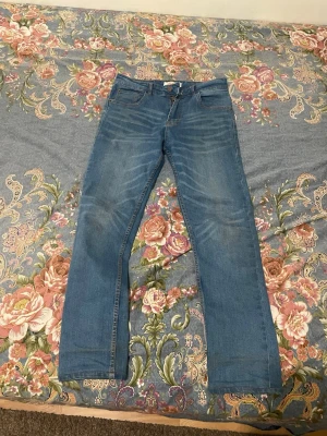 Blå raka Levis jeans med klassisk passform - Säljer ett par blå Levis  jeans med rak passform och klassisk femficksdesign. Jeansen har en snygg tvätt med lätt slitning framtill och bakfickor med enkel söm. Perfekta till vardags och passar till det mesta. Materialet är denim i bomull.