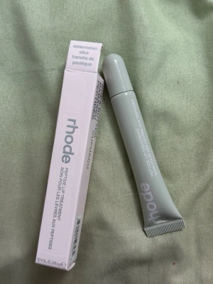 rhode Peptide Lip Treatment Watermelon - Peptide Lip Treatment från rhode i smaken Watermelon Slice. Läppbalsamet kommer i en stilren, ljusgrå tub med skruvkork och rymmer 10 ml. Förpackningen är modern och enkel, perfekt att ha i väskan för återfuktade läppar hela dagen.