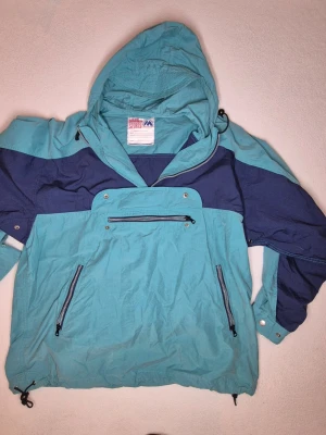 Marwin Sports anorak pullover jacka retro 90-tal vintage strl L - Klassisk 90-tals outdoor-stil med huva, halv dragkedja framtill, magficka samt två dragkedjefickor framtill. Broderad Marwin Sports-logga på bröstet/magfickan   Alla dragkedjor, knappar och snörspännen fungerar som de ska. Inga fläckar vad jag kan se. Fint begagnat vintage-skick enligt bilder.  Material: 80% bomull, 20% polyamid Storlek: Large  Mått liggande: Bröstbredd: ca 60 cm Längd axel till nederkant: ca 75 cm Ärmlängd axel till handled: ca 58 cm 
