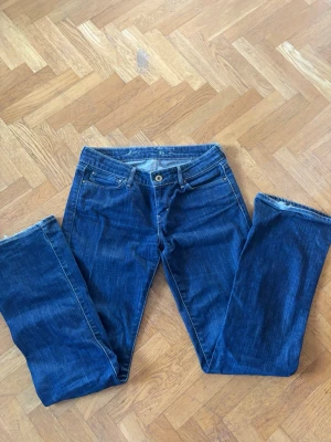 Vintage Mörkblå Levi's  - Säljer ett par klassiska mörkblå jeans från Levi's med raka/ lite utsvängda ben och fem fickor. Jeansen har snygga kontrastsömmar och en ikonisk läderpatch bak i midjan. Perfekta till vardagslooken och tillverkade i slitstarkt denimtyg.