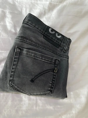 Grå slim fit jeans med detaljer - Jag säljer dessa asfeta exklusiva DonDup jeans med unika mönster. Jeansen har två bakfickor, en liten metall-detalj och en unik vit logga på linningen. Perfekta för dig som gillar en stilren men ändå edgy look. 