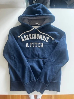 Abercrombie & fitch hoodie marinblå vintage (eftertraktad) - Riktigt snygg och eftertraktad Abercrombie & fitch hoodie. fint skick inga fel storlek L kan även passa M kan ta mått vid behov. Endast 425kr ej hugget i sten kom gärna med frågor och prisförslag har även mycket mer liknande i min profil alla storlekar kolla gärna stor rabatt vid köp av flera 😁✌️