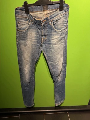 Blå slim fit jeans med slitningar - Snygga blå slim fit jeans med slitna detaljer och klassisk femficksdesign. Jeansen har ljusa tvättade partier och kontrastsömmar, vilket ger en trendig och avslappnad look. Perfekta för dig som gillar en modern och bekväm stil. Ett hål i skrevet men är lagat så de märks bara om du kollar noggrant 😁