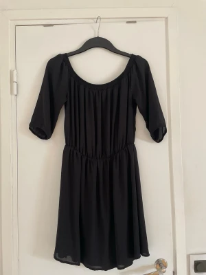 Svart kortklänning  - Säljer en svart kortklänning från BikBok. Klänningen har trekvartsärm och rundad halsringning eller offshoulder om man föredrar det. Materialet är lätt, flödande tyg som ger en luftig känsla. 